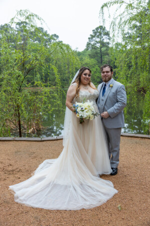 Kyle and Rebecca's wedding at Forever Five Event Venue, capturing a serene moment by the water with the couple holding hands and smiling.
