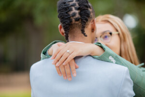 Rodney and Shauna's engagement at Hermann Park, showcasing their love and engagement ring in a tender embrace